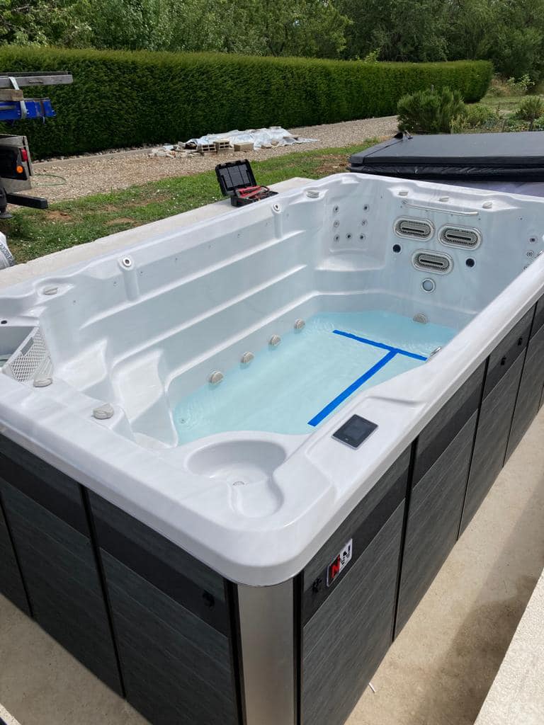 Pose d'un spa de nage Waterloo 410 dans un jardin, manutention avant mise en place